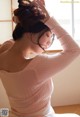 A woman in a pink sweater is sitting on the floor.