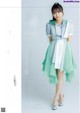 A woman in a green and white dress posing for a magazine.
