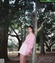 A woman leaning against a tree in a park.