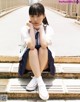 A young woman sitting on the side of a road.