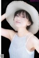 A woman wearing a straw hat poses for a picture.