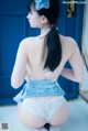 A woman in a blue and white lingerie sitting on the floor.