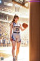 A woman holding a basketball in front of a basketball hoop.