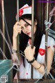 A woman dressed as a nurse behind bars with a spider web.