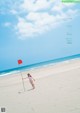 A woman walking on a beach holding a red flag.