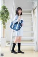 A woman in a school uniform holding a blue bag.