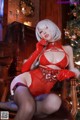 A woman in a red lingerie sitting on a chair next to a Christmas tree.