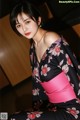 A woman in a black and pink kimono posing for a picture.