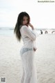 A woman in a white dress standing on a beach.