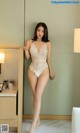 A woman in a white lingerie posing in a hotel room.