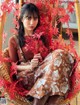 A woman sitting in a wicker chair surrounded by red leaves.