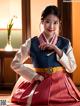 A woman in a korean dress sitting on a table.